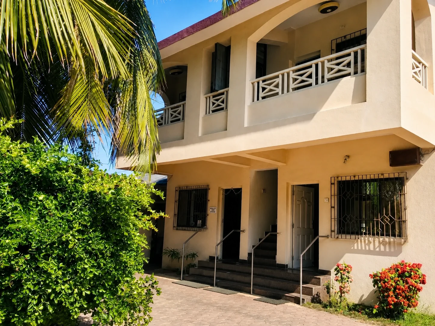 Hotel balconies and a sunlit courtyard beneath palm trees.